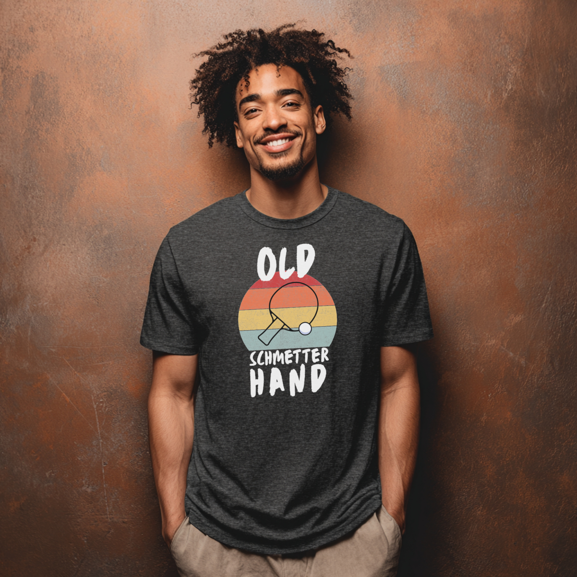 Dunkelgraues Unisex T-Shirt mit 'Old Schmetterhand' Spruch und Tischtennisschläger Motiv.