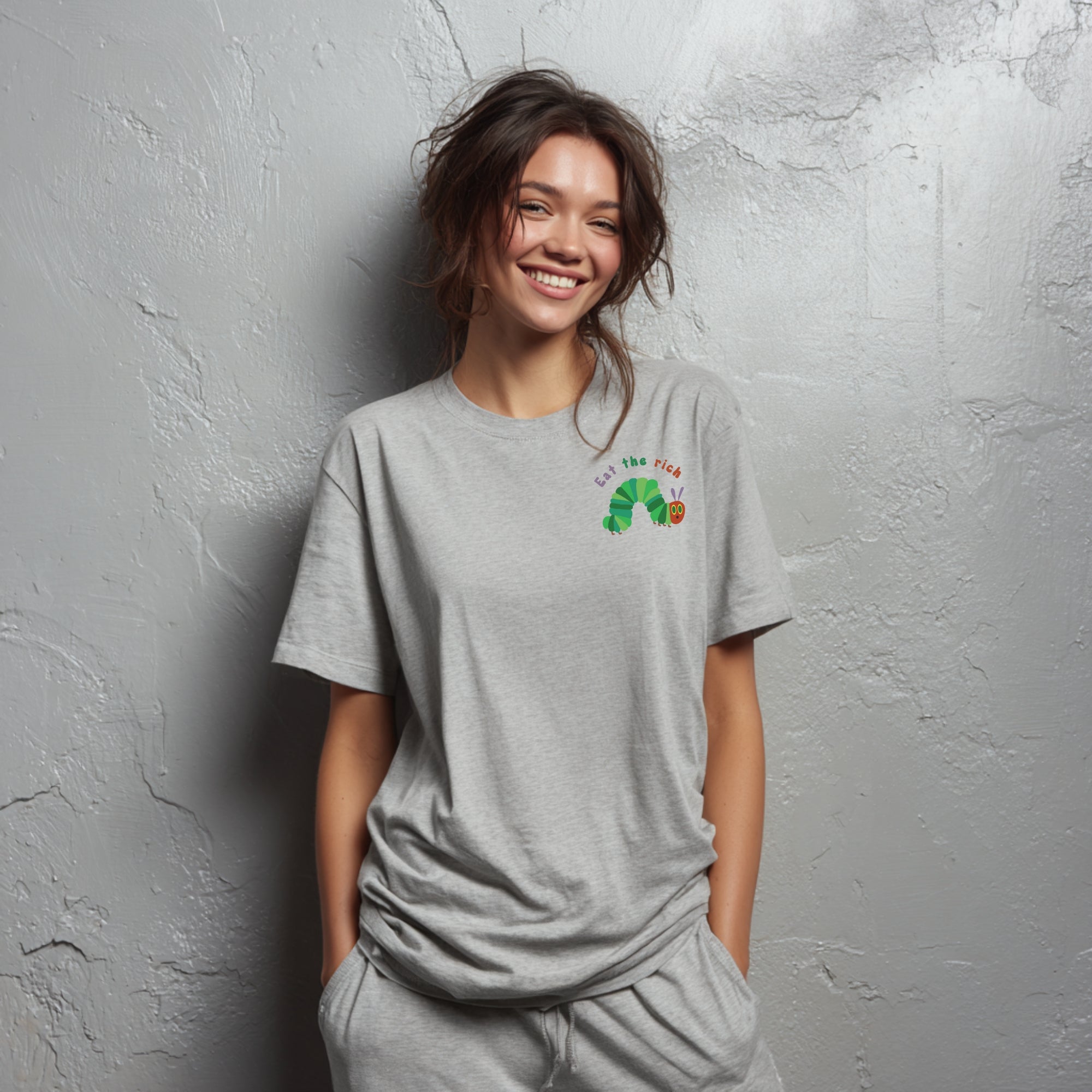 Modell trägt hellgraues T-Shirt mit Raupe Nimmersatt und „Eat the Rich“ Brustaufdruck, politisches Statement-Shirt