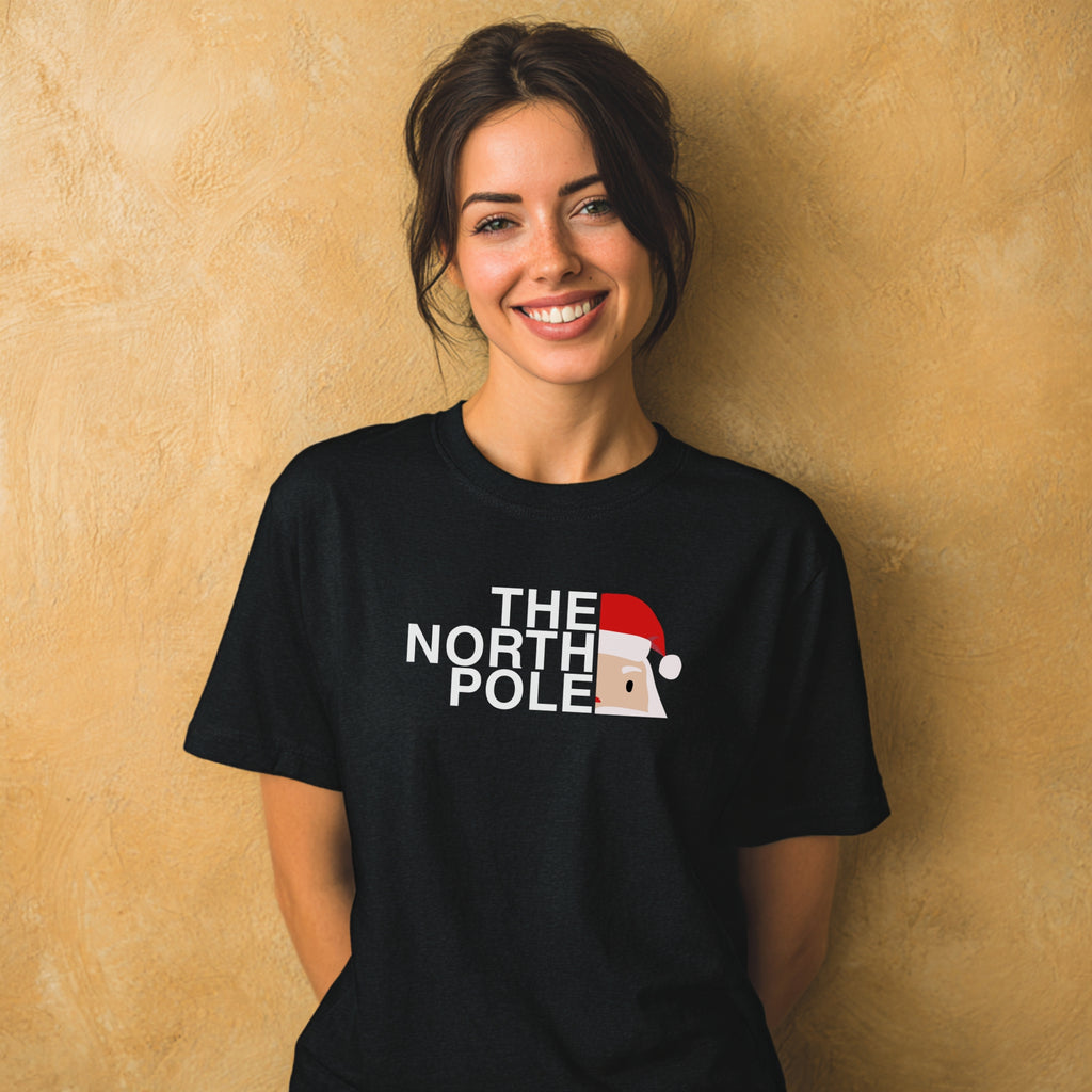Modell trägt schwarzes T-Shirt mit „The North Pole“-Aufdruck, lustiges Weihnachtsmotiv